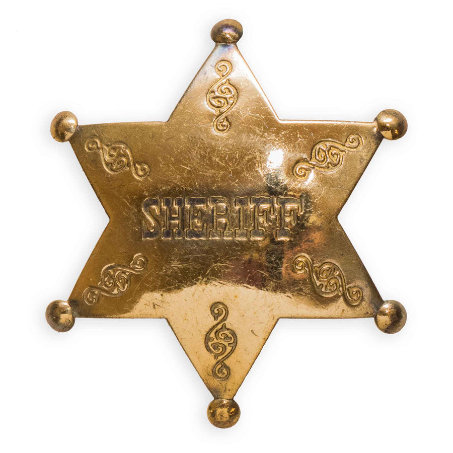 A solid brass sheriff's badge with an embossed 'SHERIFF' text in the center and decorative elements around the border.