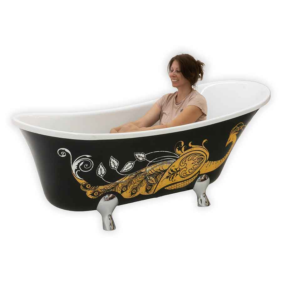 Woman sitting in a black bathtub with a gold peacock design on a white background