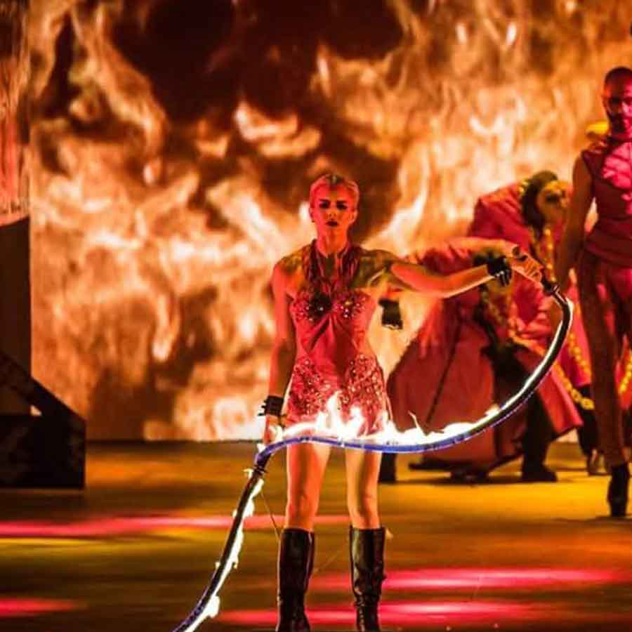 woman fire performer on stage surrounded by flames holding fir whip - category image. 