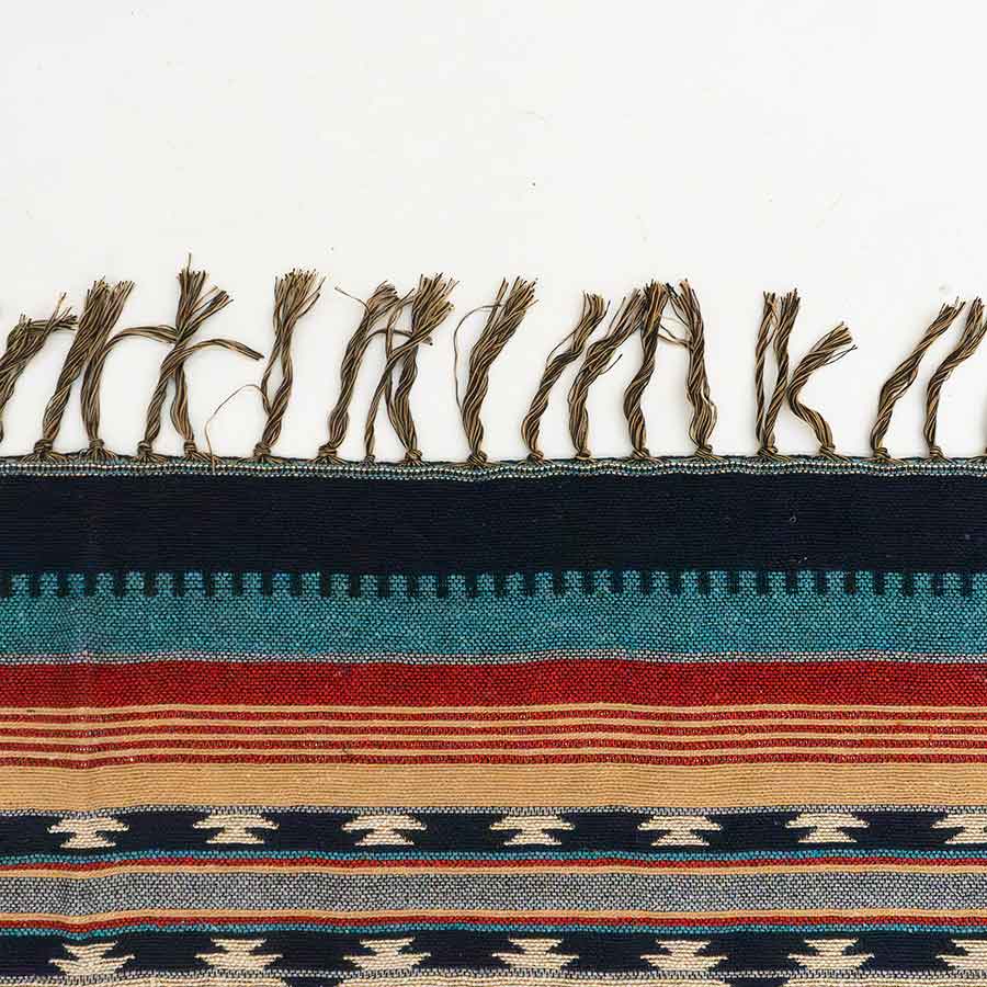 Close-up of a woven textile with striped pattern and fringed edge on a white background